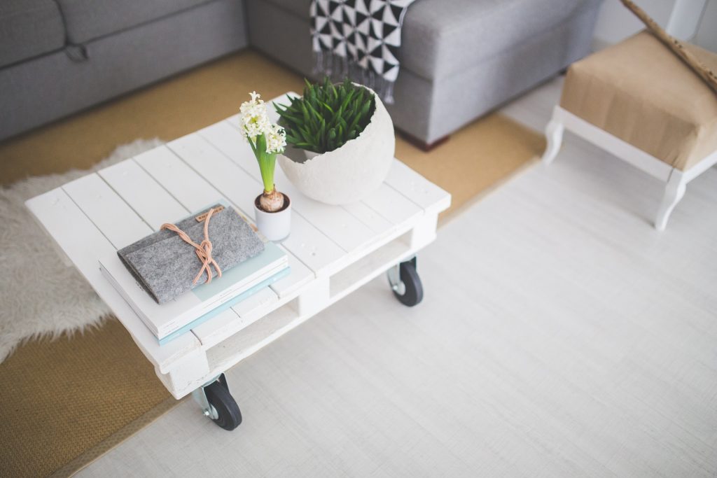 Table basse en bois blanc et plantes dans un salon clair